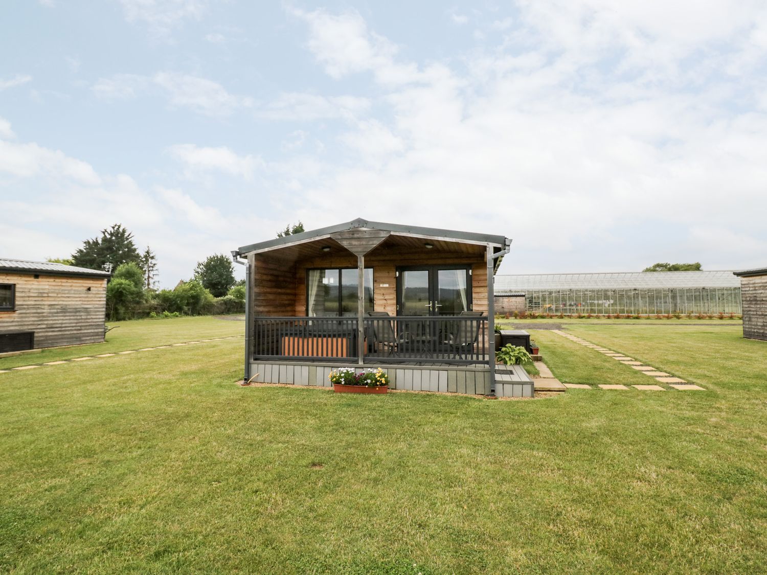 Cotswold View 3 cabin with small porch and railing on a sunny day
