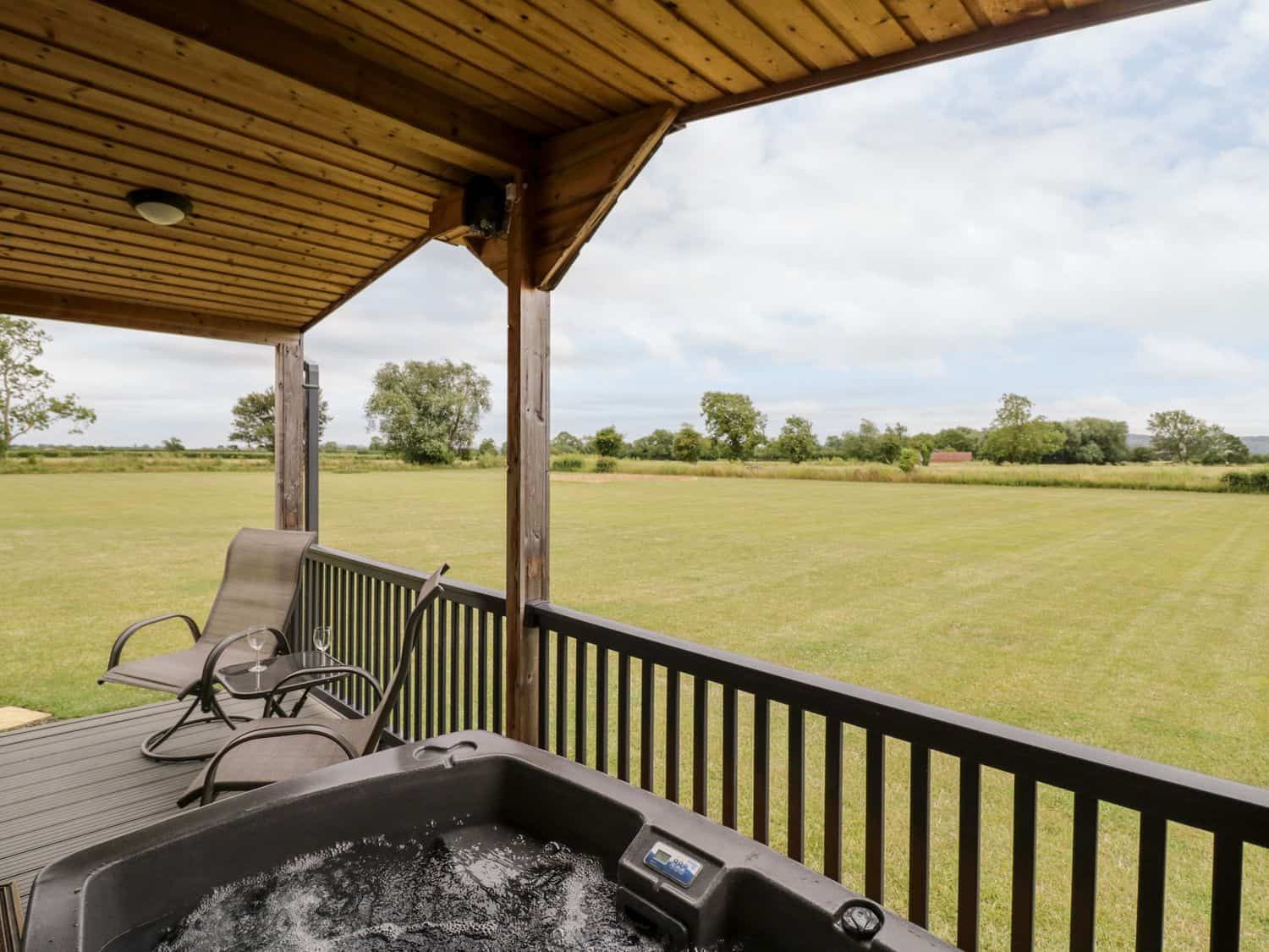 Covered outdoor deck with hot tub and two chairs at Cotswold View 3