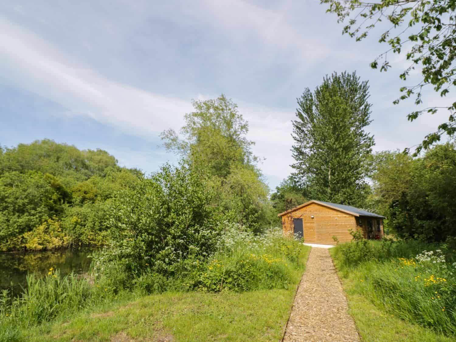 Dragonfly wooden cabin at the end of a gravel path surrounded by greenery