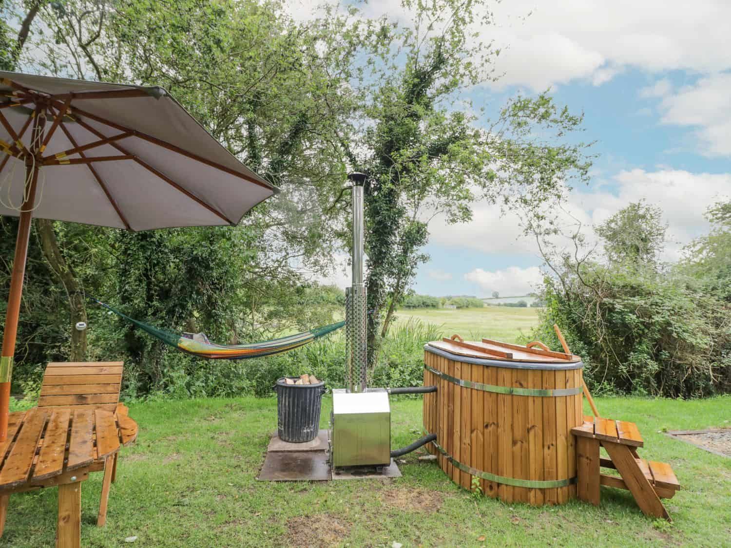 Outdoor garden area with wooden hot tub and hammock at Dragonfly