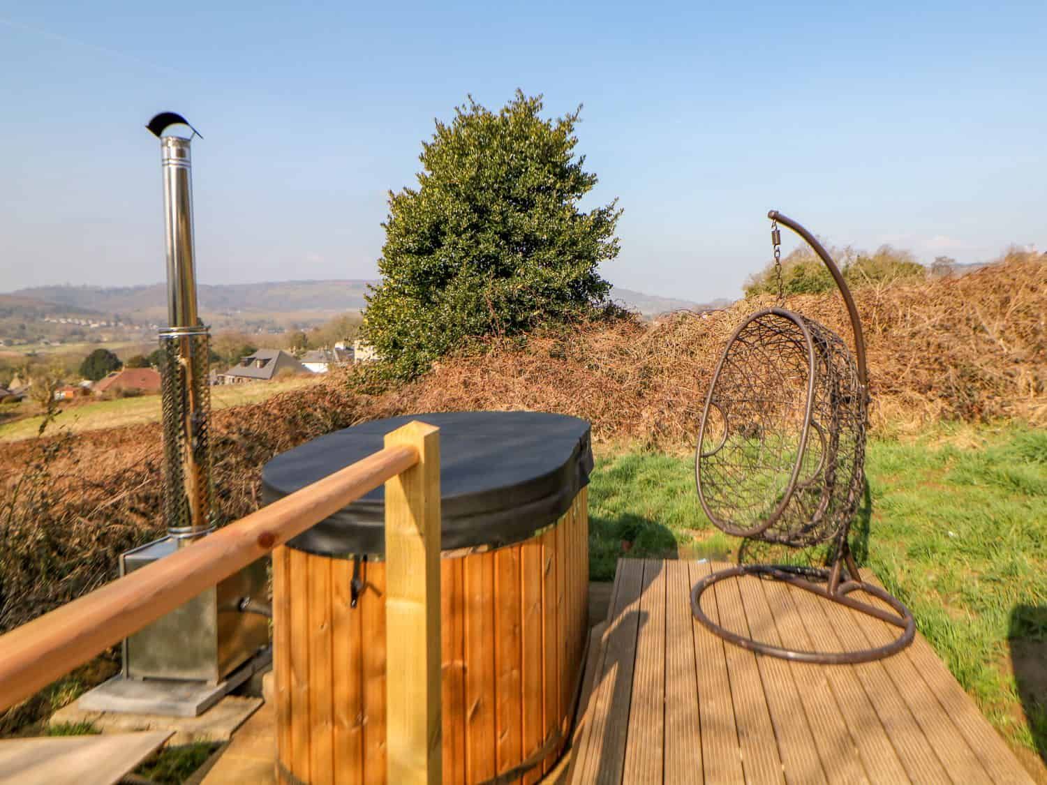 Wood-fired hot tub on decking with sweeping views across Peak District hills at Holbein