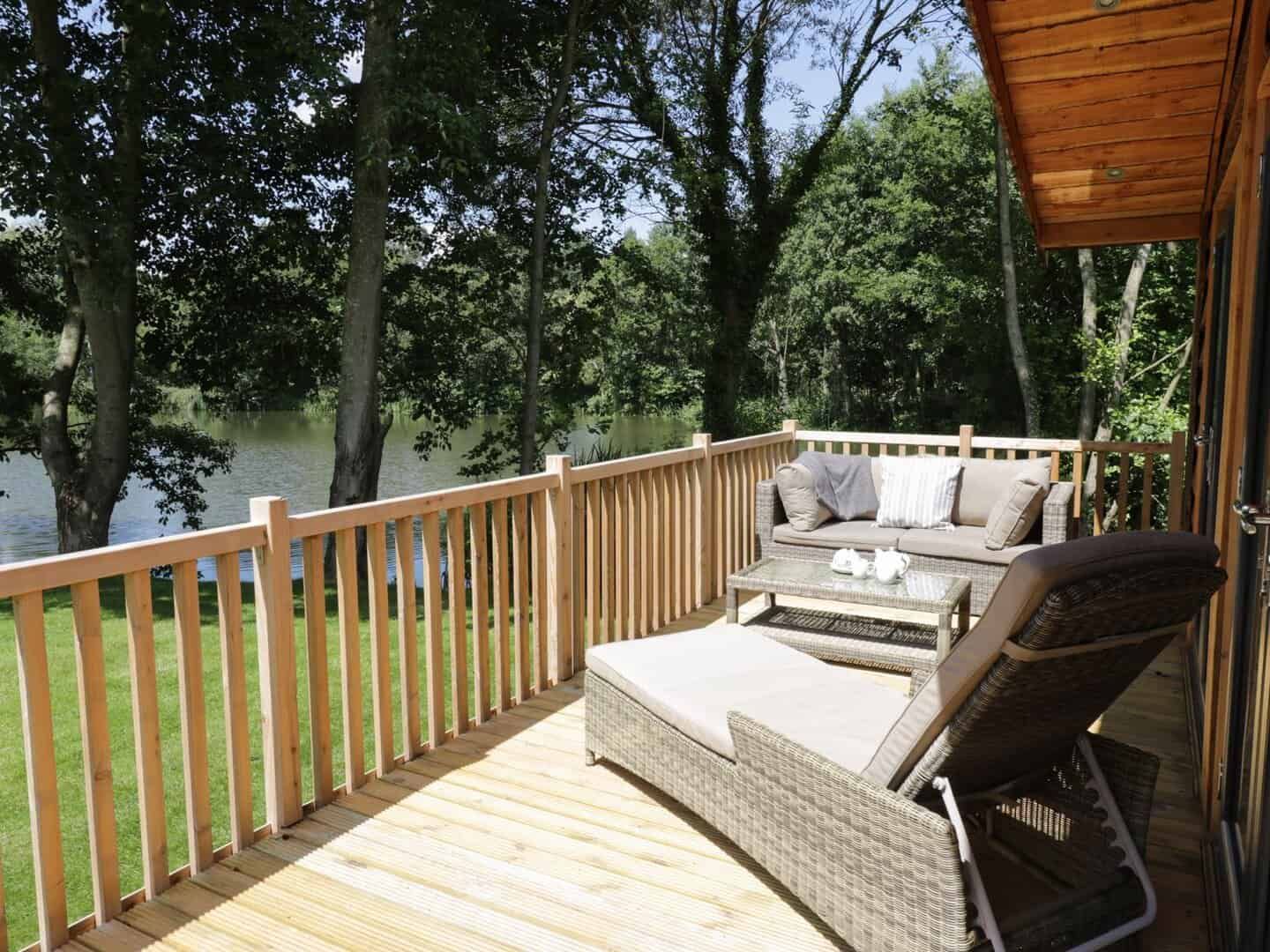 Wooden balcony with outdoor furniture overlooking the lake at Kingfisher lodge