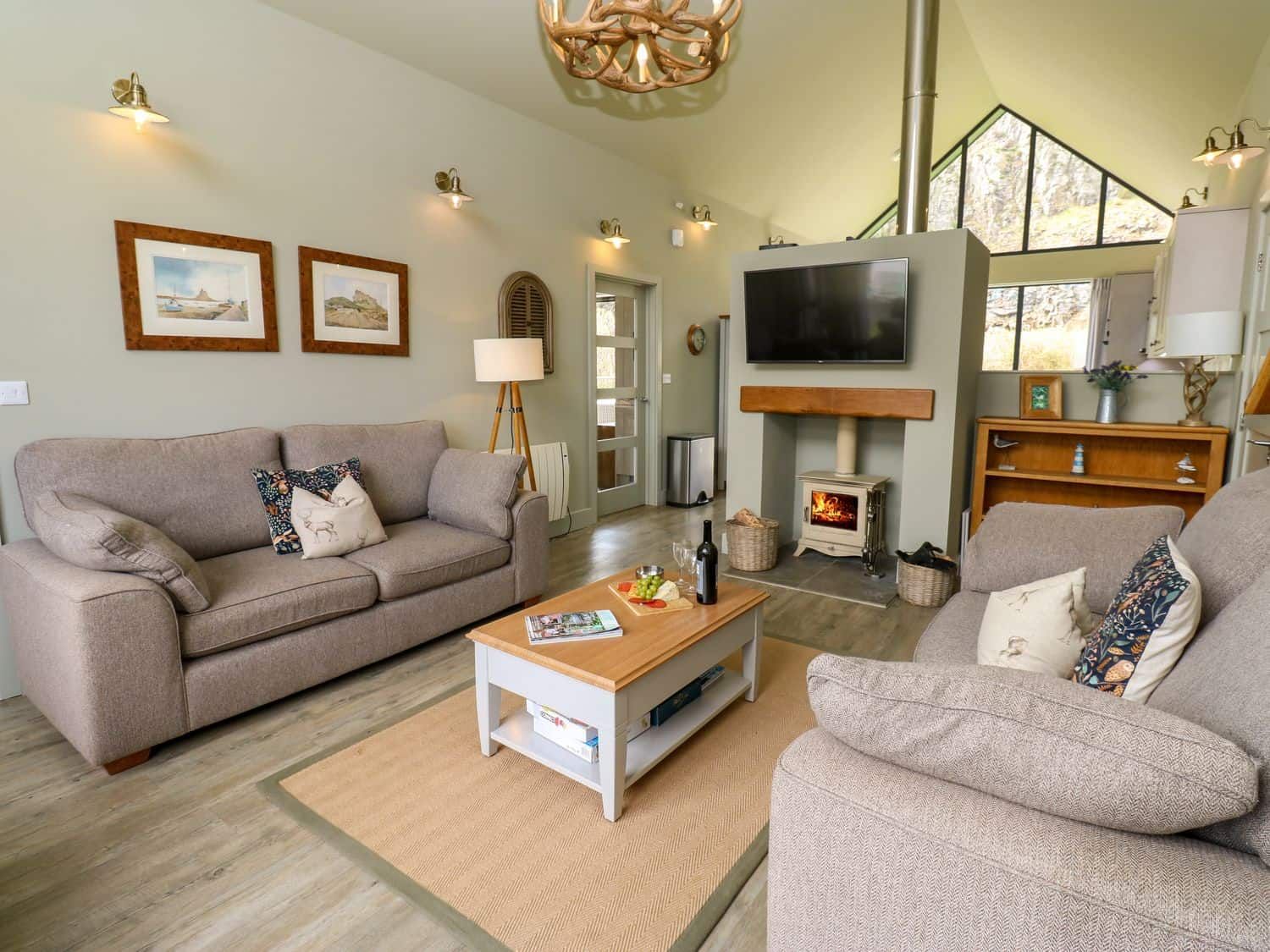 Open plan living area with woodburner and comfortable sofas at Restharrow Lodge