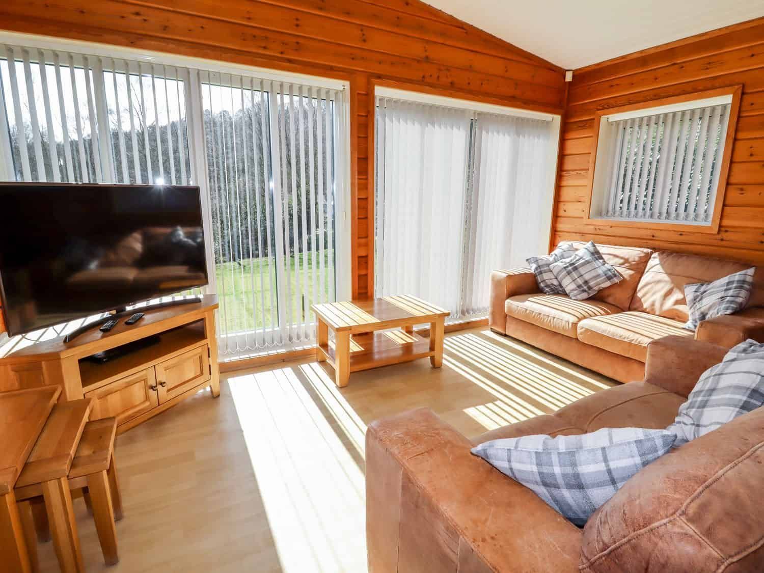 Wood-panelled living area with Smart TV and comfortable sofas at Watersview Lodge