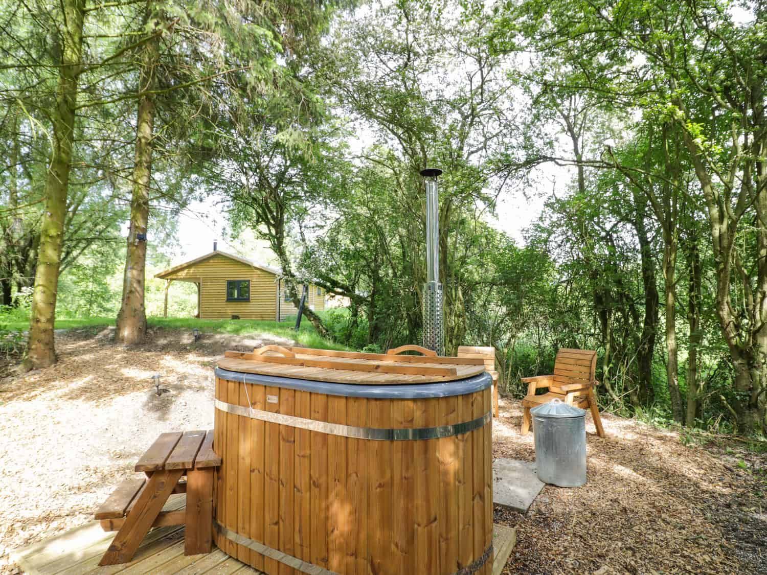 Outdoor area with wooden hot tub and wooden chair at Willow lodge